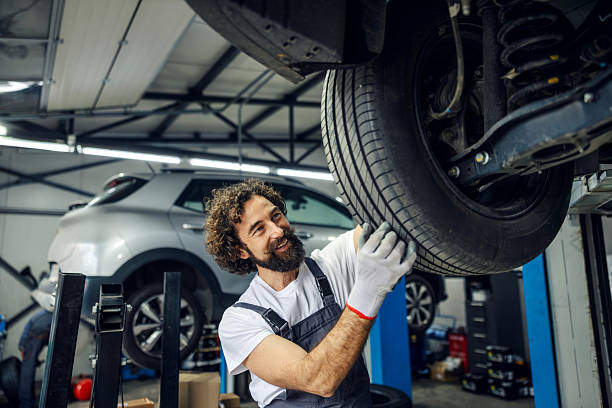 istock Mechanic inspecting car tire in auto service garage 2247184303