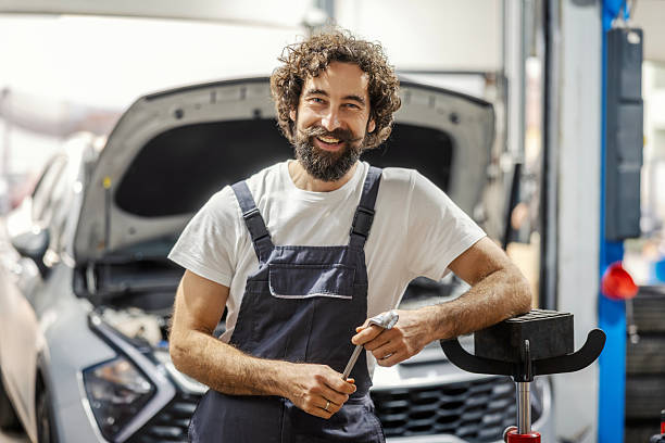 istock Auto mechanic smiling standing in front of car 2247184461