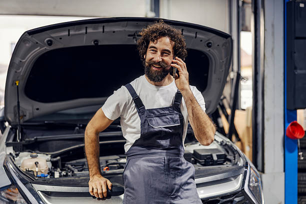 istock Mechanic talking on smartphone with car hood open 2247184500