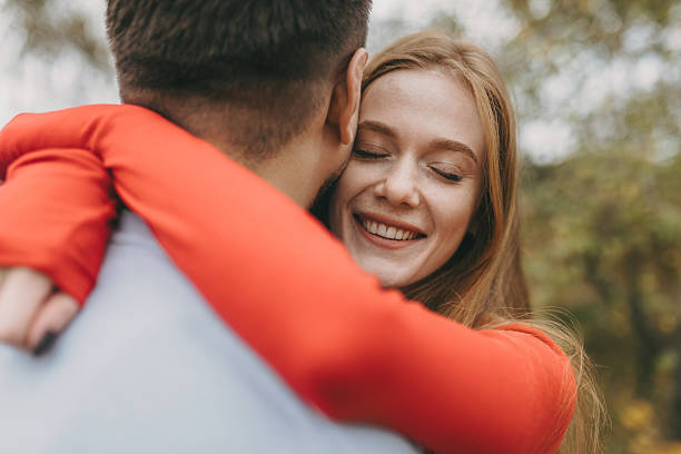 istock laughter and warmth as woman in crimson sweater hugs her partner outdoors during fall scene 2247185512