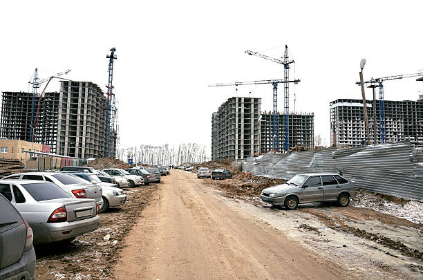 Tower crane, road and new building silhouettes under construction at construction site at white sky background