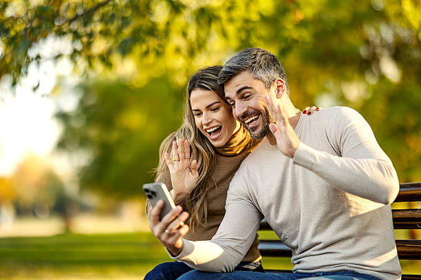 istock Happy couple making video call waving hands in park 2247186561
