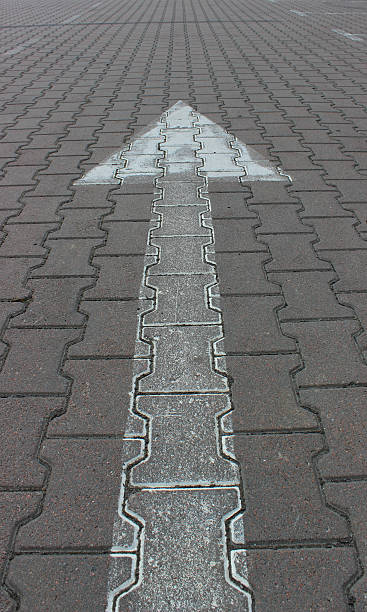 istock White drawn arrow going into the distance on the pavement tiles vertical photo 2247189678