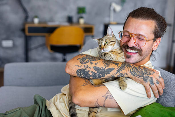 istock Relaxed man sitting on the sofa at home while gently petting his cat 2247190236