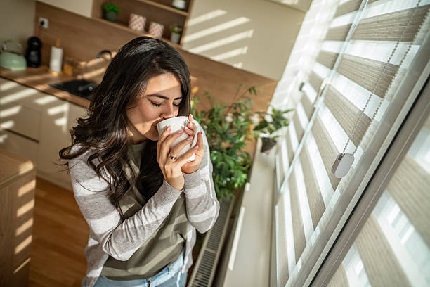 istock Woman enjoying morning coffee in sunlit kitchen at home 2247190736