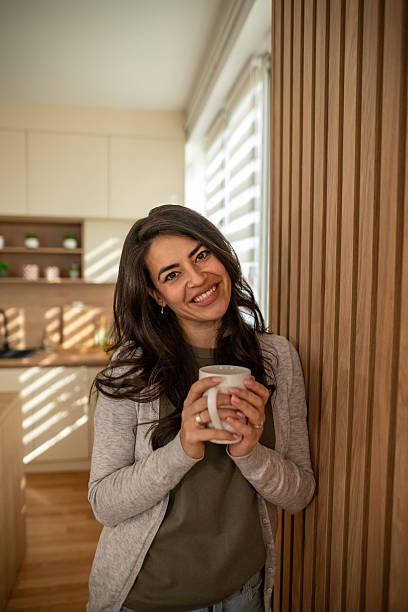 istock Woman smiling holding coffee mug enjoying morning light 2247190763