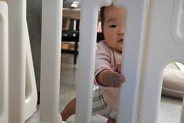 istock A 0-year-old baby peers at us through a baby gate. 2247195564