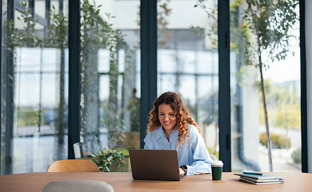 istock Smiling Woman Working On Laptop At Modern Office Desk With Coffee Cup And Notebook 2247197634