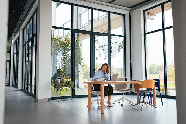 istock Professional Woman Working at Modern Glass Office Desk With Laptop, Documents and Coffee 2247197653