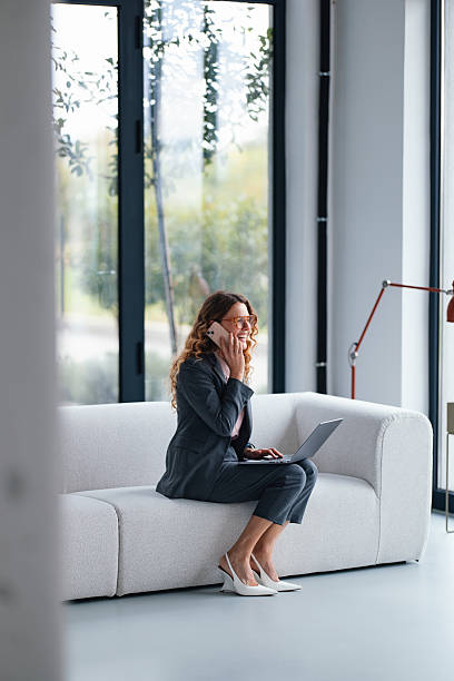 istock Confident Businesswoman On Sofa With Laptop During A Phone Call In Modern Office Environment 2247197785