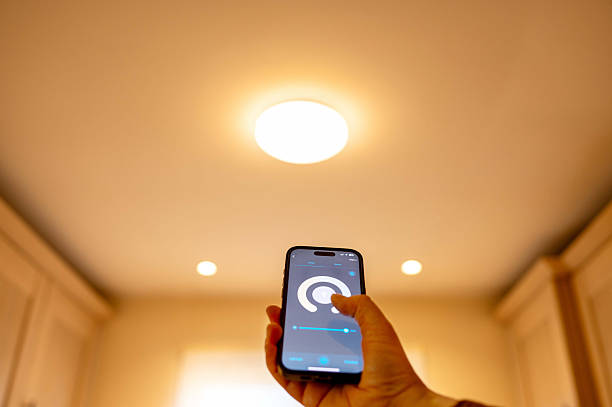 istock Woman controlling smart lighting at home using smartphone. Concept: smart home, control lighting from smartphone. 2247200102