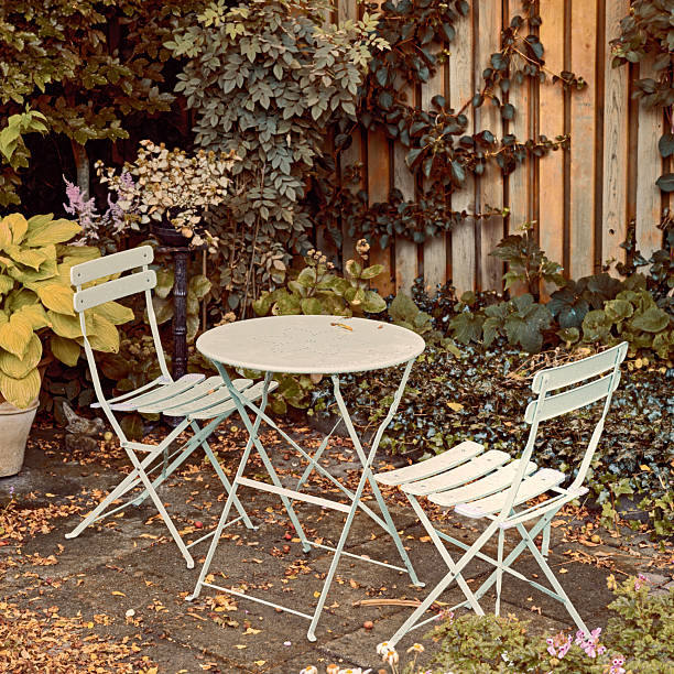 istock Charming Garden Setting with Green Bistro Table, Chairs, and Lush Foliage 2247202906