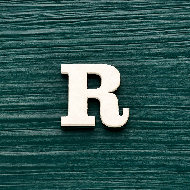 istock Alphabet letter R, white piece on a dark green rustic background 2247203563