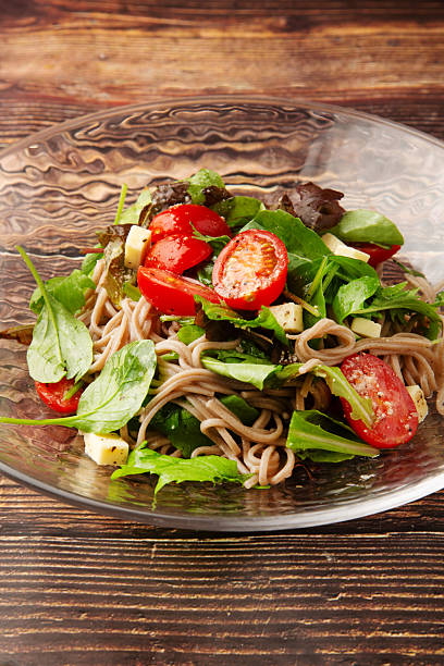 Soba noodles topped with tomato, cheese, and green salad