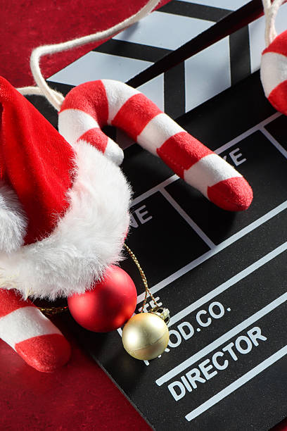 istock Full frame image black and white film clapperboard, string of candy canes, red and gold Christmas bauble ornaments, Santa hat, mottled red background, elevated view, Christmas film concept 2247208923
