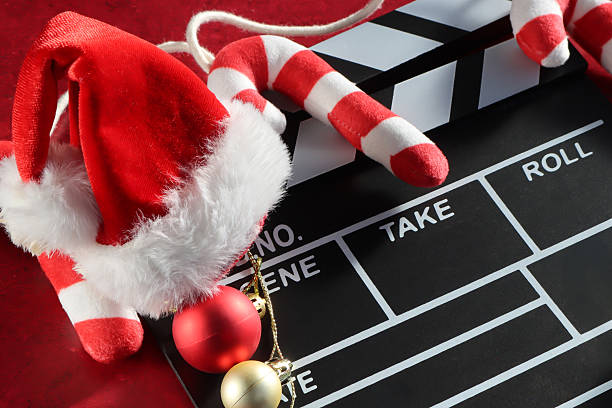 istock Full frame image black and white film clapperboard, string of candy canes, red and gold Christmas bauble ornaments, Santa hat, mottled red background, elevated view, Christmas film concept 2247208946