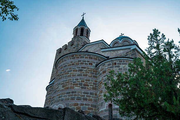 Historic Patriarchal Cathedral rising above old stone fortress walls on Tsarevets Hill in Veliko Tarnovo, bathed in afternoon sun.
