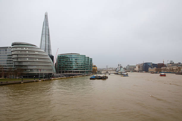 The Thames river, The Shard pyramid style modern skyscraper office tower building, HMS belfast boat and the waterfront of downtown London, England.