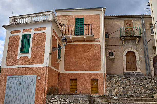 istock Stone steps leading to rustic Italian houses with green shutters under cloudy sky 2247225563