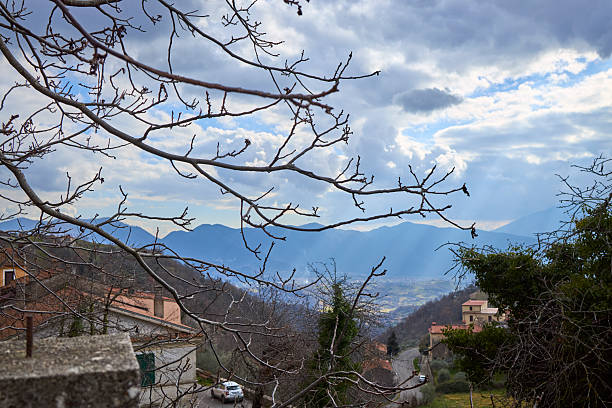 istock Narrow mountain road below Italian village, with distant valley and clouds 2247227527