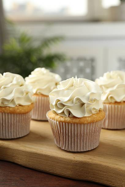 istock Tasty cupcakes with vanilla cream on wooden table, closeup 2247229074