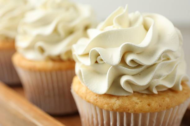 istock Tasty cupcakes with vanilla cream on table, closeup 2247229077