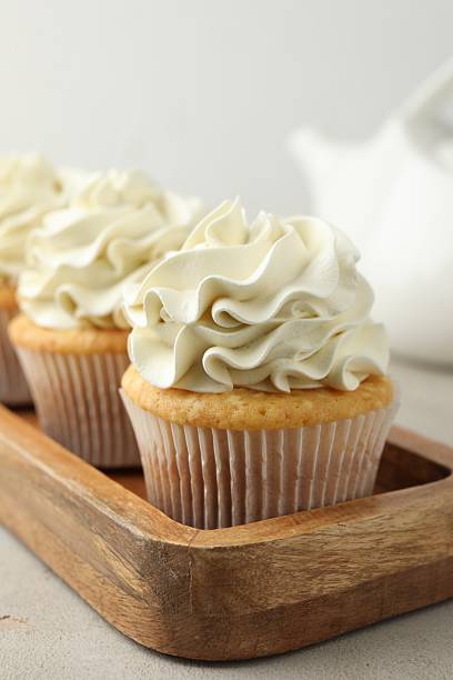 istock Tasty cupcakes with vanilla cream on light grey table, closeup 2247229104