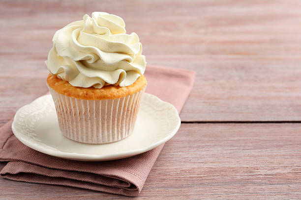 istock Tasty cupcake with vanilla cream on pink wooden table, closeup. Space for text 2247229113