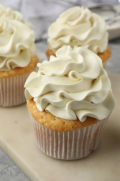 istock Tasty cupcakes with vanilla cream on grey table, closeup 2247229116