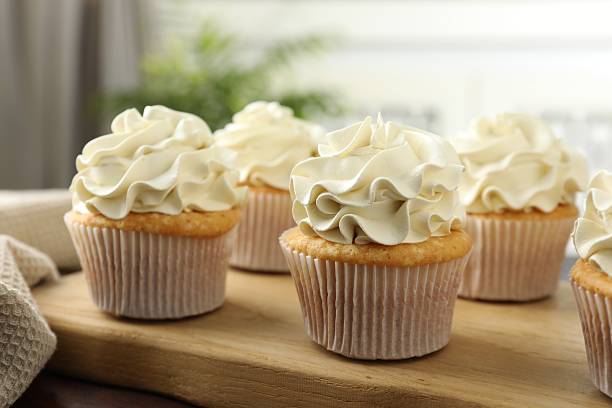 istock Tasty cupcakes with vanilla cream on wooden table, closeup 2247229124