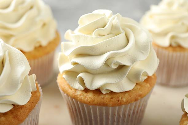 istock Tasty cupcakes with vanilla cream on table, closeup 2247229139
