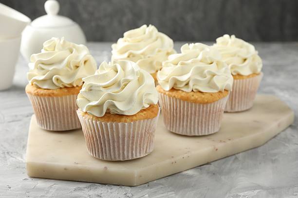 istock Tasty cupcakes with vanilla cream on grey table, closeup 2247229153