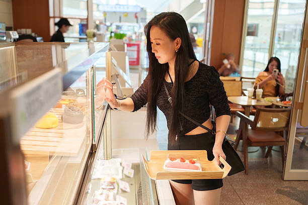 istock An Asian woman selecting snacks in a store. 2247229315