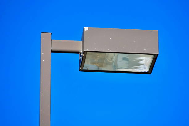 Close-up of a street light in a parking lot against a clear blue sky background on a sunny day.