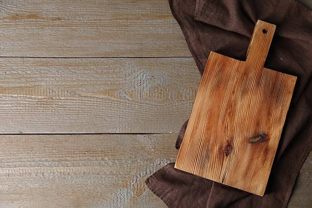 istock Cutting board and napkin on wooden table, top view. Space for text 2247233224