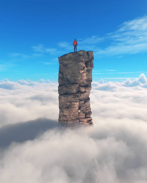istock Climber standing on a tall rock formation above the clouds during a clear day in a mountainous region 2247234272
