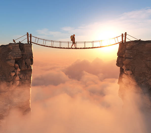 istock Hiker walking across a stunning suspension bridge over clouds during sunset 2247234275