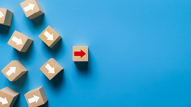 istock wooden blocks with irregular white arrows and one red arrow pointing right direction isolated on blue background. leadership concept 2247235200