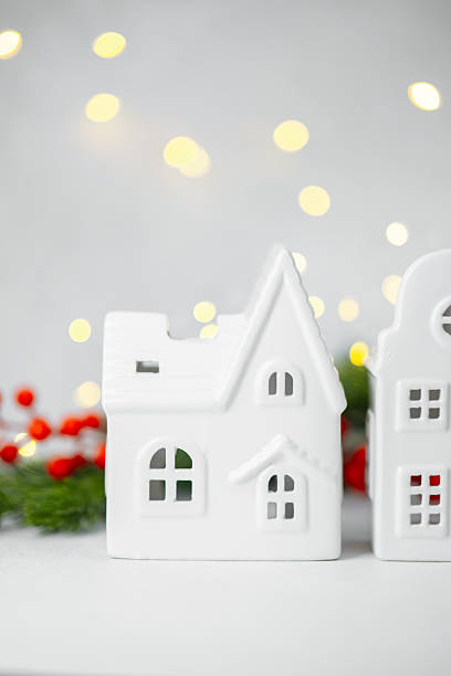 istock White ceramic house village display with festive red berries and blurred yellow lights. 2247235301