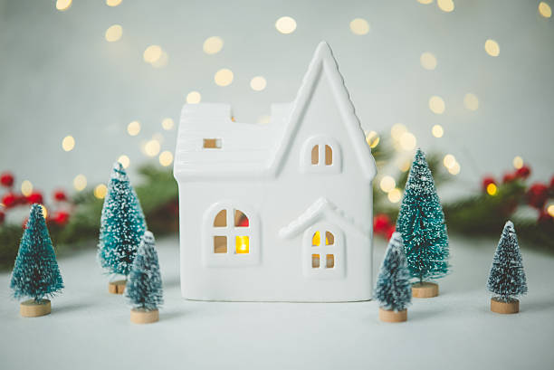 istock Tiny ceramic house and decorated pine trees with festive background lights 2247235306