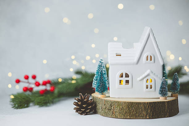 istock White ceramic house decoration with small pine trees, red berries and warm light, festive background. 2247235319