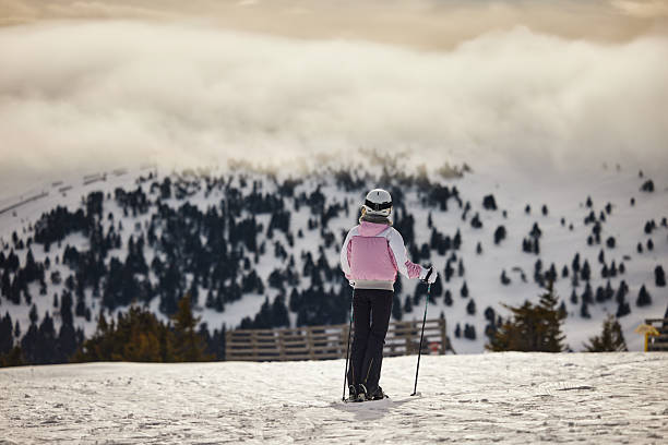 Women, girl in winter overalls,ski mask,glasses with skis,on snow hill looking at high Carpathian mountains at winter alpine ski resort holiday, outdoor nature landscape, Ukraine, Europe.aerial view.
