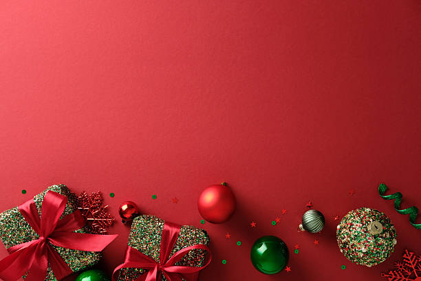 istock Christmas flat lay composition: gifts, ornaments, and confetti creating a festive bottom border on red background. 2247236725