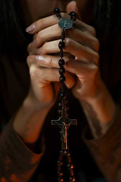 istock Woman praying in dark holding rosary beads 2247237026