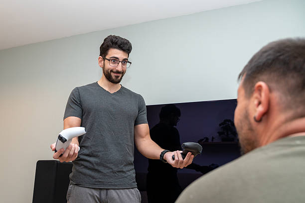 istock Young man holding ps vr2 controllers, offering them to a friend for an immersive virtual reality gaming experience 2247237727