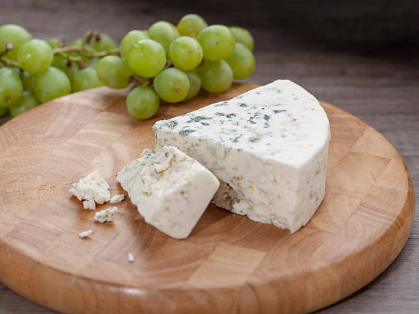 Blue Cheese Wedge with Crumbles and Green Grapes on Wooden Board