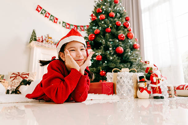 istock Joyful child in red sweater opens presents near sparkling Christmas tree. Ornaments, lights, ribbons, and laughter fill the cozy living room with noel warmth, togetherness, and festive excitement. 2247239663
