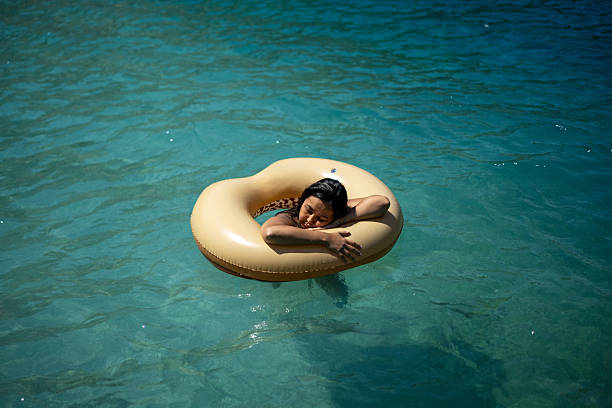 Elegant young woman in retro style sunglasses swimming in pool with floating ring. Relaxation. Contemporary art collage. Summer, retro, surrealism, creativity, travelling concept