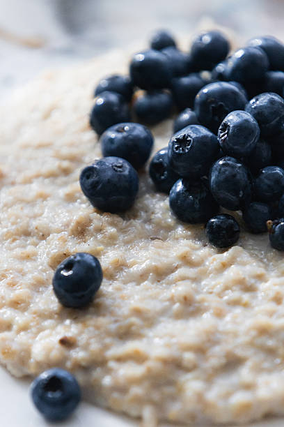 young man sitting comfortably on his sofa while enjoying a healthy serving of blueberries accompanied by a little oatmeal