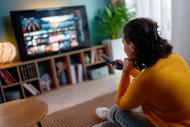 istock woman watching TV at home 2247243220